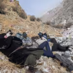 Snow Leopard tour 2024, by Teo Allofs Snow Leopard tour participants lying on a mountain in Western Mongolia, scanning the landscape with binoculars in search of the elusive cat.