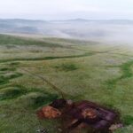Xianbei tomb site in Orkhon Aerial shot of archeological digging site for ancient tomb that dates back Xianbei period on a green steppe with Mongolian ge in a background, in Orkhon soum in Selenge province.