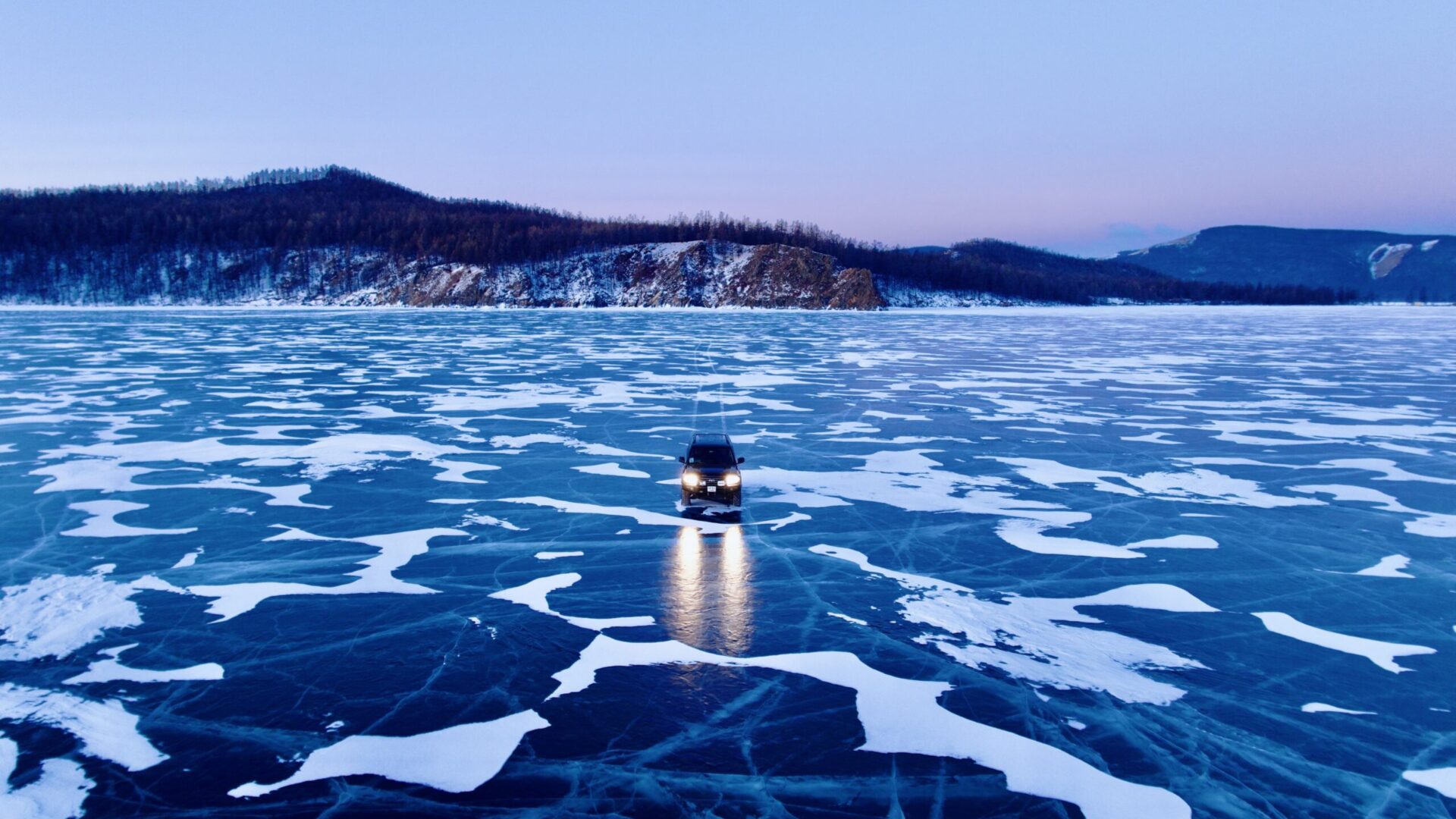 Land Cruiser driving on frozen khuvsgul lake, Mongolia's dark blue pearl.
